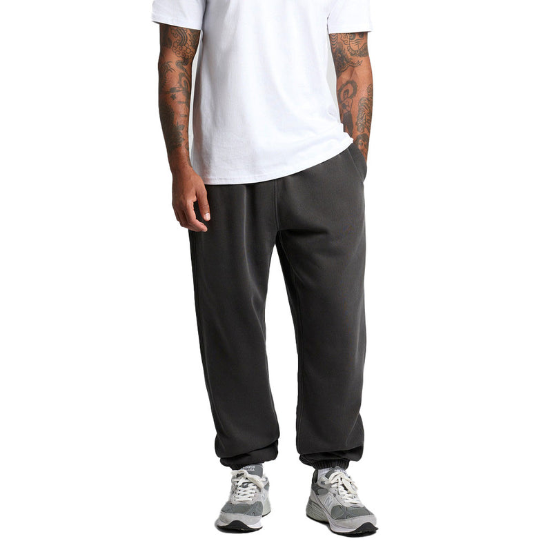 Load image into Gallery viewer, The AS Colour Relax Faded Track Pants, shown on a tattooed model, feature a relaxed fit with elastic cuffs, highlighting comfort and style, perfect for casual or active settings.