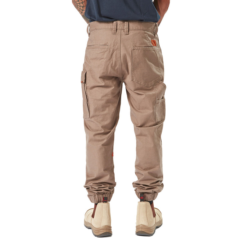 Load image into Gallery viewer, Volcom Workwear Caliper Cuffed Pant showcased with reinforced knees, tapered leg, and utility pockets, embodying durability and style, suitable for demanding work environments. Featured alongside tan boots for a complete workwear look.