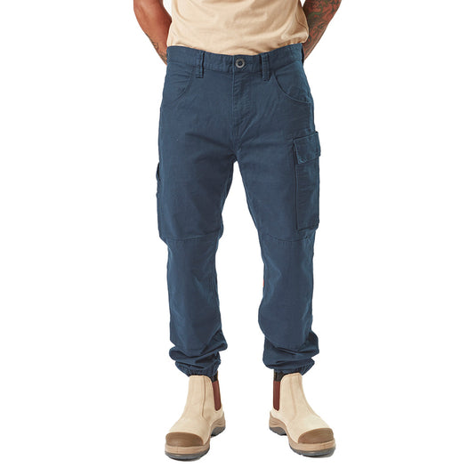 Volcom Workwear Caliper Cuffed Pant featuring durable design with reinforced knees and multiple utility pockets, ideal for active safety environments. Modeled by a person standing, showcasing comfort elastic cuffs.