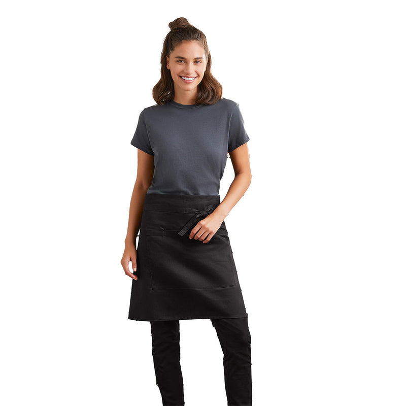 Load image into Gallery viewer, The Biz Short Waisted Apron, Black, features a sleek design with a large central pocket and towel loop, worn by a woman demonstrating its practical fit and professional style. Ideal for workplace use.