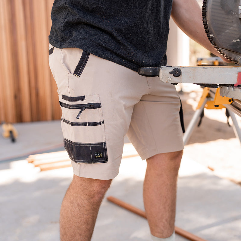 Load image into Gallery viewer, Bisley Flex & Move 4-Way Stretch Zip Cargo Short designed for durability with Cordura® reinforcement and multi-functional pockets, ideal for work environments. Modeled by a man holding a tool, showcasing flexibility.