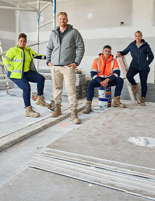 A group of workers on a building site wearing their workwear and hi vis uniforms. This showcases Active Safety's commitment to offering a diverse range of uniform for hi vis and workwear applications for both men and women. They are all wearing Safety Boots which is a core part of the Safety Equipment & Workwear offering at Active Safety.