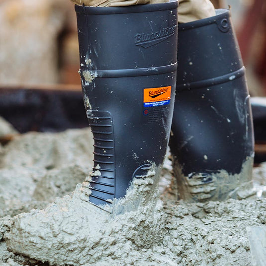 A concrete worker wearing their Blundstone Safety Gumboots with concrete covering the outside of the gumboot. A great gumboot for working with concrete due to the tough materials and Blundstone's commitment to making high quality footwear.