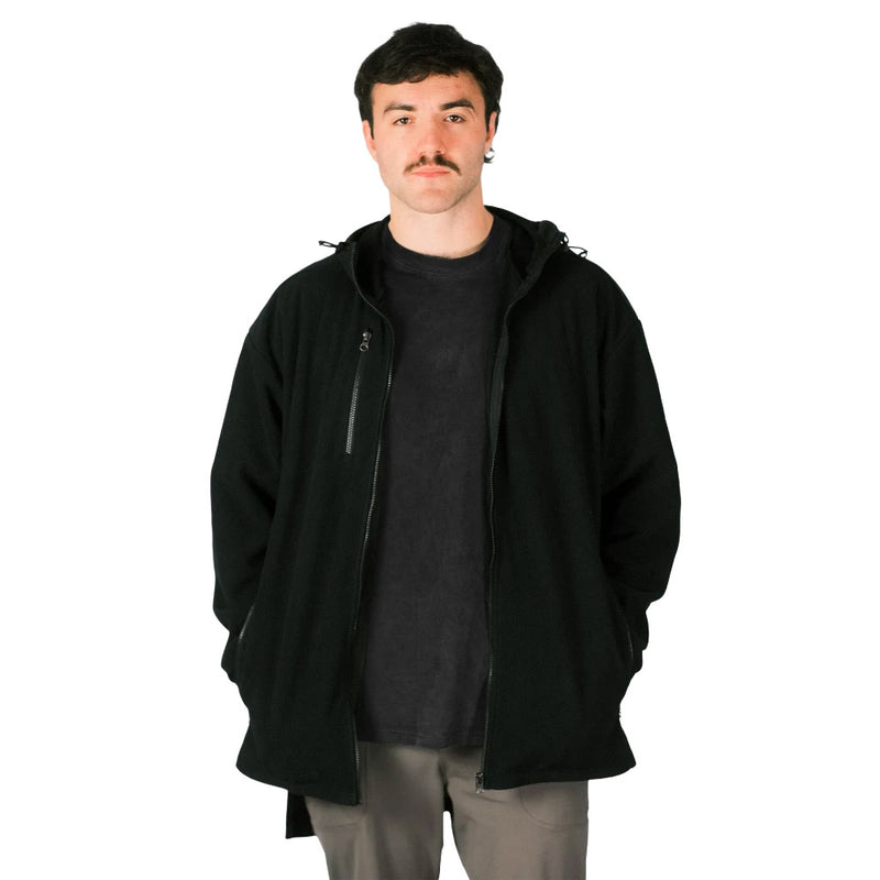 Load image into Gallery viewer, Young adult male models the Cloke Hauroko Windproof Full Zip Long Sleeve Fleece, showcasing its adjustable hood, YKK zip, and hands in pockets, highlighting its active safety features.