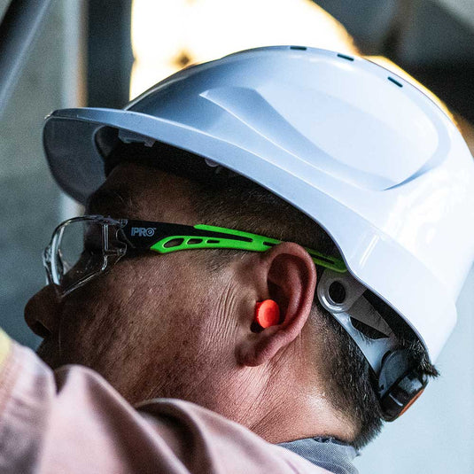 A close up of a worker wearing a white hard hat on their head for head protection in the workplace.
