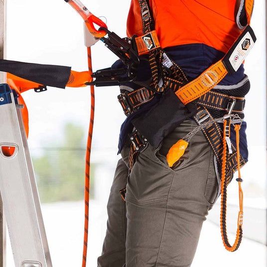 A close up of a worker climbing a ladder against a pole while wearing a hi vis LINQ safety harness. The safety harness is assisting in fall protection for extra safety at the workplace. These products are part of the Height Safety category.