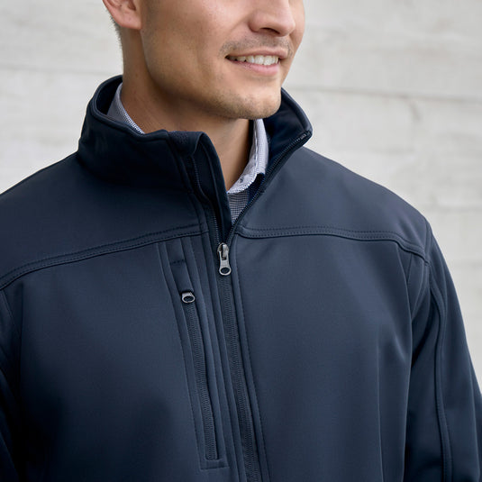 Biz Mens Soft Shell Jacket showcased on a model, highlighting its stand-up collar, zippered chest pocket with audio port, and adjustable cuffs, ideal for safety-focused workwear needs.