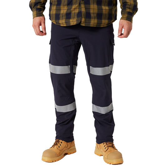 Jetpilot Jet-Lite Stretch Tape Utility Pant, Navy, featuring diagonal reflective striping on thighs and lower legs, paired with light brown work boots. Ideal for safety-conscious outdoor activities and work environments.