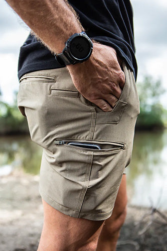 The Jet-Lite Hybrid Elastic Waist Short features a person showcasing its reinforced front entry pockets, secure zip-lock pockets, and heavy-duty waistband, ideal for active safety and workplace needs.
