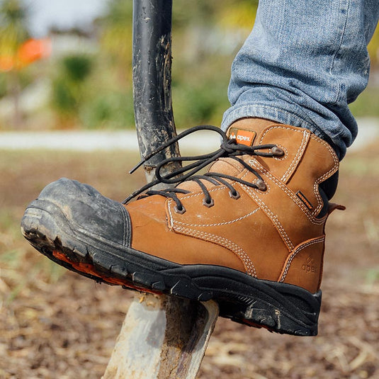 A person wearing an Apex Safety Boot, using the sole of the boot to press the spade into the ground beneath. This shows the quality of the Apex Safety Work Boot range and that it is up to the task for hard wearing work.