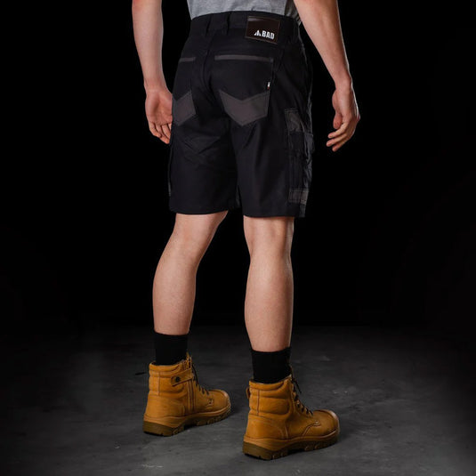 Man wearing BAD Attitude Slim Fit Work Shorts with reinforced pockets and a smartphone pocket, paired with brown boots, showcasing workwear functionality and style.