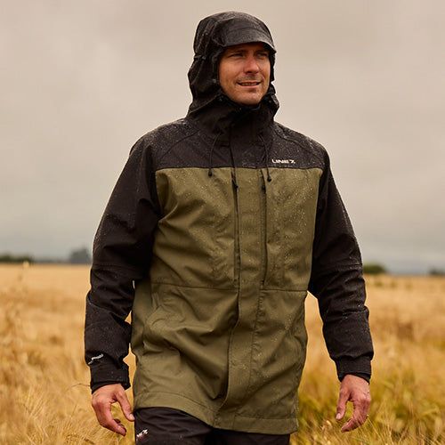 Load image into Gallery viewer, Line 7 Territory Storm Pro20 Waterproof Jacket featuring a fixed hood, double storm flap, and multiple waterproof pockets, ideal for outdoor safety and protection, showcased by a man standing outdoors.