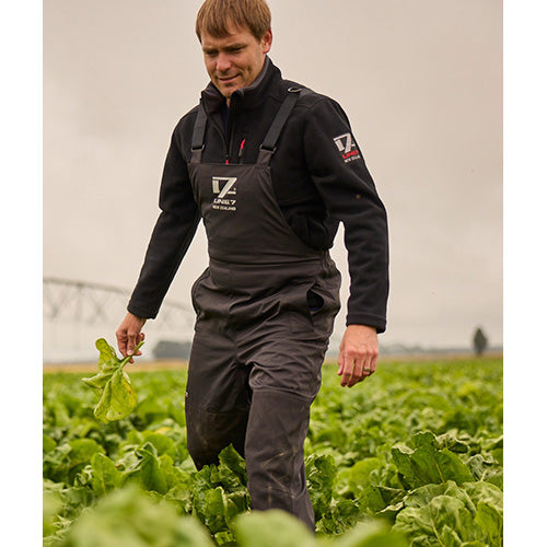 Load image into Gallery viewer, Line 7 Territory Storm Pro20 Waterproof Bib Overtrouser worn by a man in a field, showcasing durable design with adjustable braces and articulated knees, ideal for farming and outdoor protection.