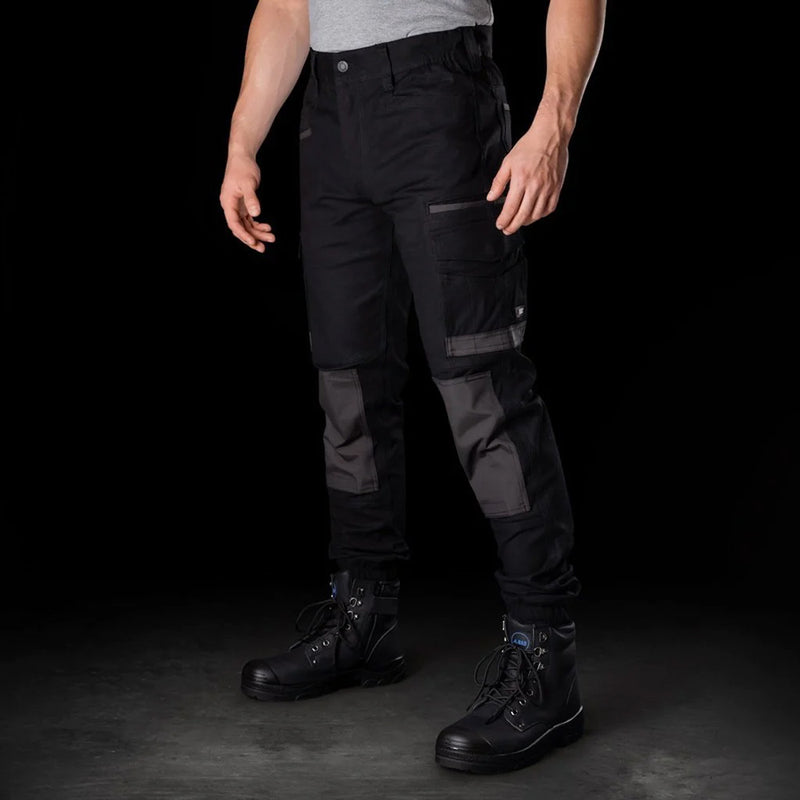 Load image into Gallery viewer, BAD Attitude Slim Fit Cuffed Work Pants, featuring a man wearing them with black boots, highlighting reinforced knees, elastic sides, and cuffed ankles, ideal for workplace safety and functionality.