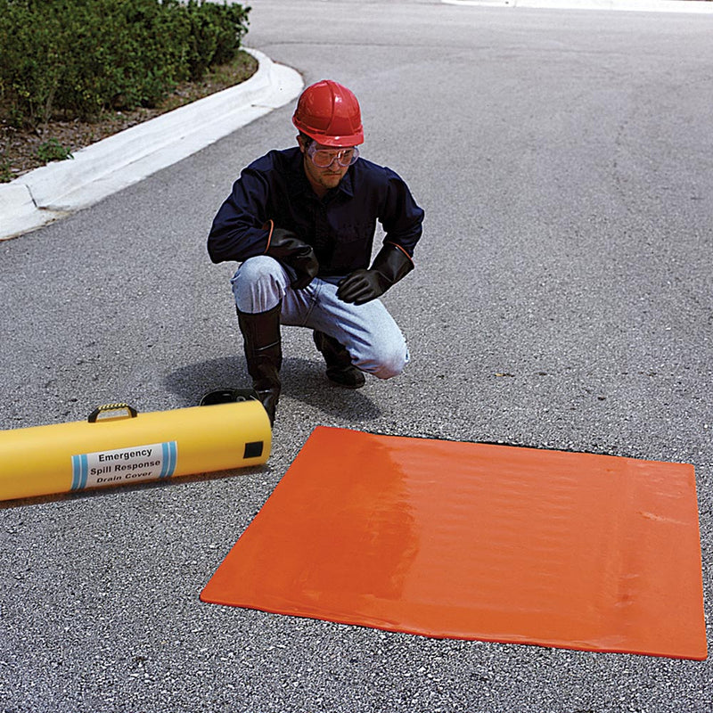 Load image into Gallery viewer, Worker in safety gear demonstrates the Ultra Drain Seal Orange 91 x 91cm, sealing a storm drain with its flexible, urethane construction. The product's yellow storage tube is visible beside him.