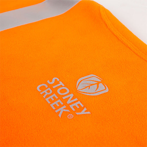 Stoney Creek Performance Plus Bush Tee, Orange/Black, featuring a close-up of its distinctive logo and durable fabric, ideal for layering under safety gear in varied weather conditions.