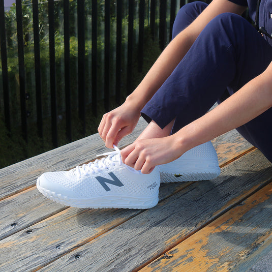 New Balance 906 SR Women's Non-Safety Shoe, White, being tied by a person, showcasing its slip-resistant outsole and flexible Hyposkin upper, ideal for workplace safety and comfort.