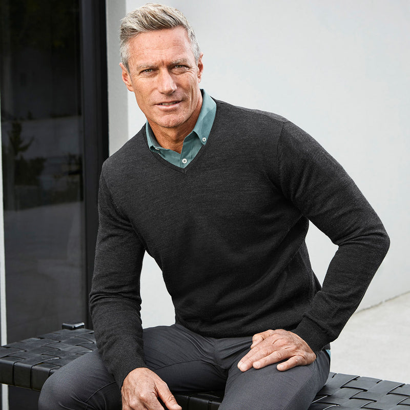 Load image into Gallery viewer, Biz Mens Roma Knit Pullover shown worn by a man sitting, demonstrating its lightweight, professional V-neck design, ideal for workplace settings. Features relaxed ribbed cuffs and hem for comfort.