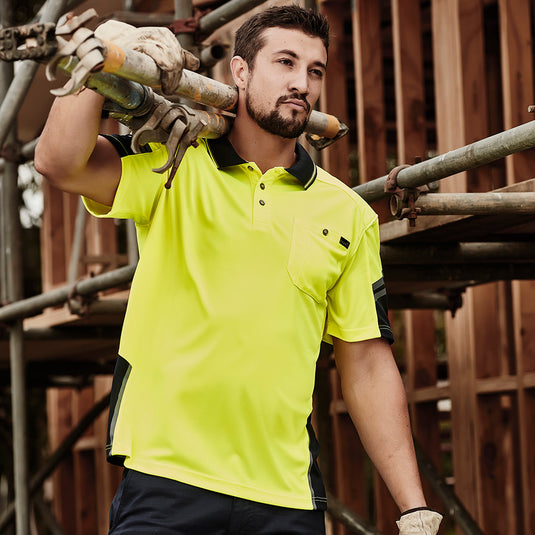 Syzmik Hi Vis Reinforced Squad Polo Shirt worn by a man, featuring reinforced shoulder areas for comfort while carrying tools, ideal for safety-focused workplaces, aligning with Active Safety's commitment to durable workwear.