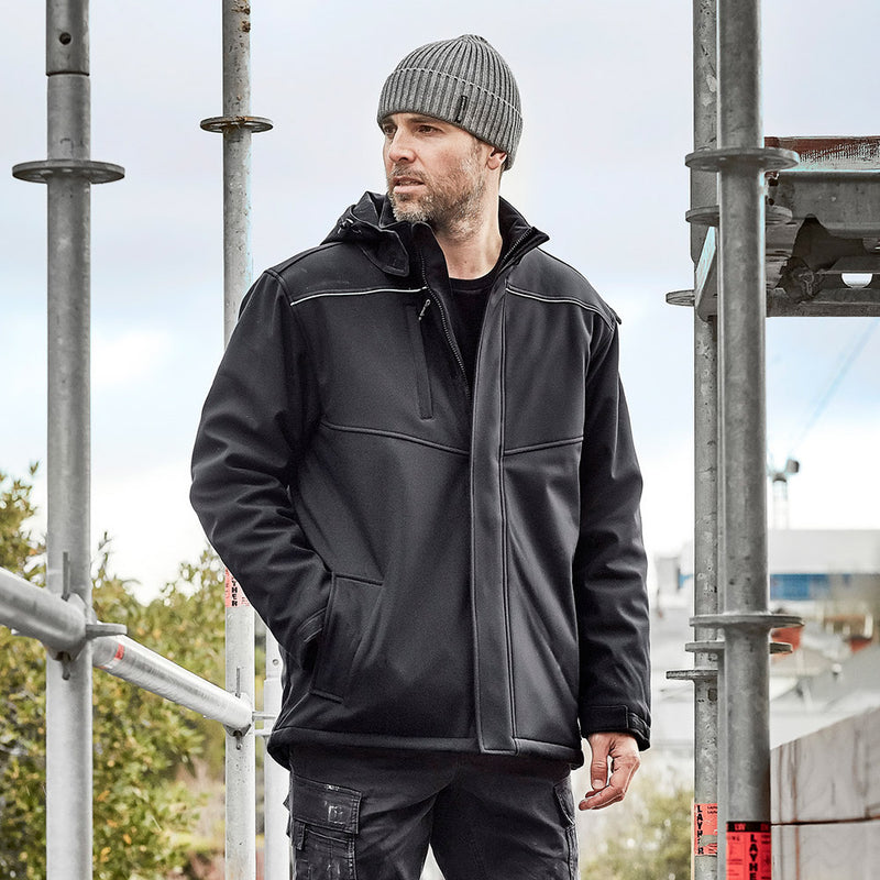 Load image into Gallery viewer, Syzmik Unisex Antarctic Softshell Jacket, featuring a zip-off hood and multiple secure pockets, worn outdoors. Designed for extreme cold protection with a storm flap and water-resistant fabric. Ideal for safety-focused environments.
