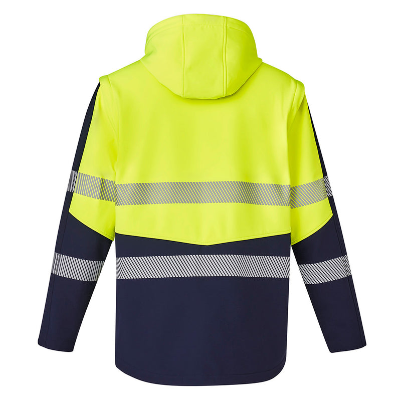 Load image into Gallery viewer, Syzmik 2-in-1 Stretch Soft Shell Taped Jacket featuring a detachable hood and sleeves, visible zip-off sections, and multiple zippered pockets, designed for versatility and comfort in safety-focused work environments.