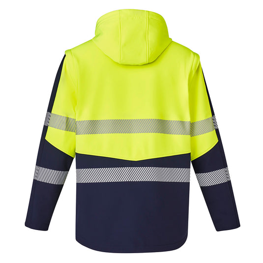 Syzmik 2-in-1 Stretch Soft Shell Taped Jacket featuring a detachable hood and sleeves, visible zip-off sections, and multiple zippered pockets, designed for versatility and comfort in safety-focused work environments.