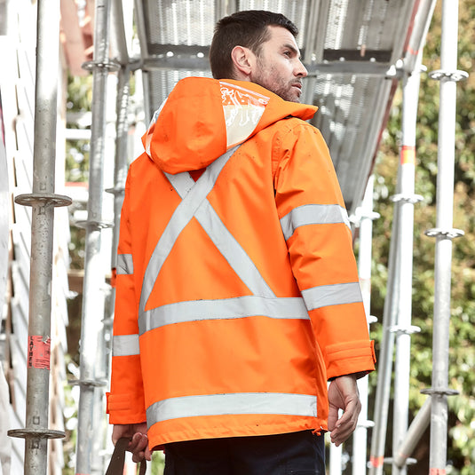 Syzmik TTMC-W23 X-Back 4-in-1 Combo showing a man in a high-visibility orange jacket with white stripes, highlighting its waterproof design and versatile, reversible vest. Ideal for safety and workwear.