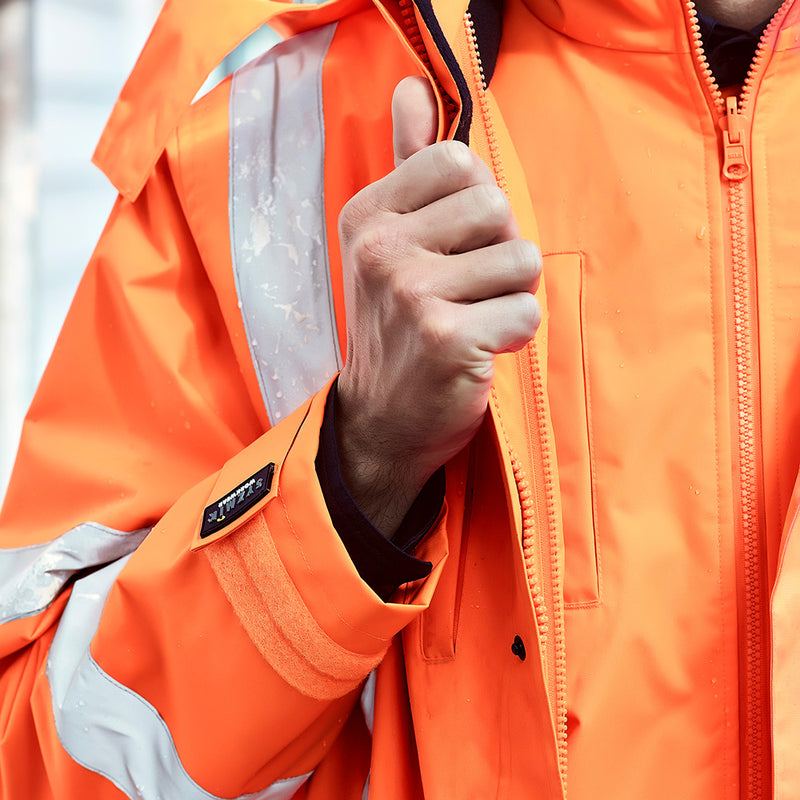 Load image into Gallery viewer, Syzmik TTMC-W23 X-Back 4-in-1 Combo, featuring a visible orange jacket with a concealed hood and zippered waist pockets, ideal for high-visibility workwear and safety applications.