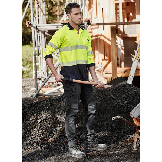 Syzmik Streetworx Stretch Pant (Non-Cuffed) worn by a man holding a shovel, showcasing its modern slim fit, unique stretch pleating, and functional pockets, ideal for active work environments.