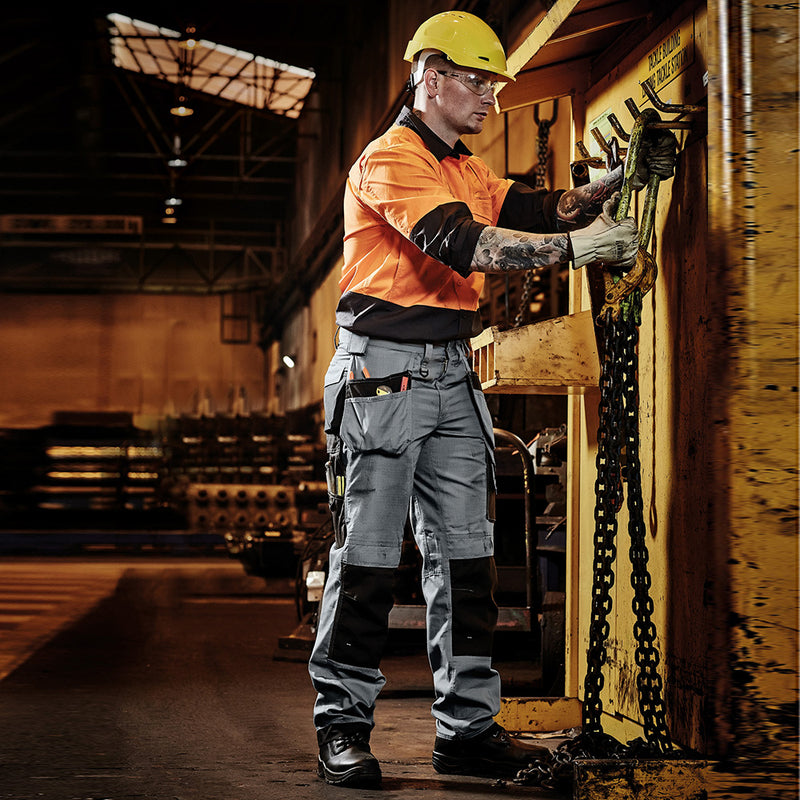 Load image into Gallery viewer, Syzmik Ultralite Multi Pocket Pant worn by a man in an orange and black uniform, featuring swing-away pockets for tool storage, demonstrating its functionality and durability in a construction setting.