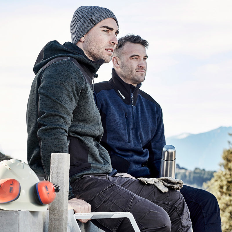 Load image into Gallery viewer, Syzmik Streetworx Knit Hoodie featuring marle knitted fleece, reinforced soft shell panels, and built-in glove cuffs. Ideal for active safety, with secure hip and chest pockets. Men sitting, showcasing the hoodie's fit.