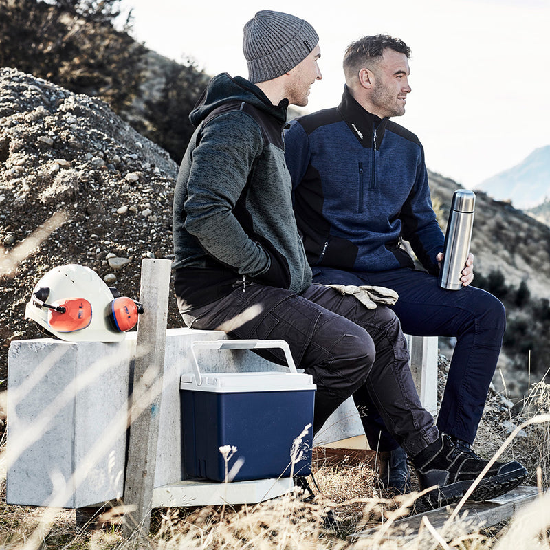 Load image into Gallery viewer, Syzmik Streetworx Knit Hoodie on a man sitting outdoors, showcasing its warm knitted fleece and reinforced soft shell panels, ideal for safety and workwear.
