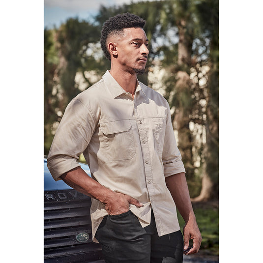 Syzmik Mens Lightweight Tradie L/S Shirt showcased on a man beside a car, emphasizing its triple-stitched seams, multiple chest pockets, and underarm vent eyelets for optimal comfort and functionality.