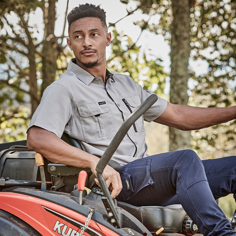 Load image into Gallery viewer, Syzmik Outdoor Ripstop Work Shirt worn by a man on a tractor, showcasing its lightweight, breathable fabric and chest pockets, ideal for active outdoor work environments.