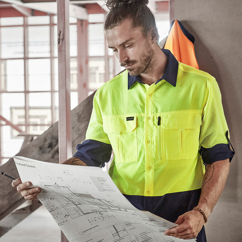 Load image into Gallery viewer, Syzmik Hi Vis L/S Outdoor Work Shirt showcased, with a man examining a blueprint. Features include roll-up tab sleeves and two chest pockets, highlighting its lightweight, breathable design ideal for workplace safety.