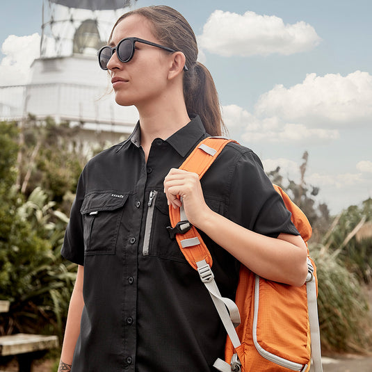 Syzmik Womens Outdoor Short Sleeve Shirt featuring lightweight, crinkle-resistant fabric with extra-large underarm mesh and back venting, two chest pockets, and a mobile phone zip pocket, ideal for active safety environments.