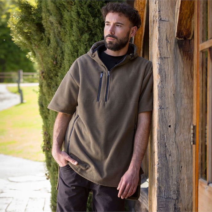Cloke Hauroko Windproof Short Sleeve Fleece on a man outdoors, showcasing its adjustable hood, super-sized pouch pocket, and breathable design, ideal for active safety and protection in windy conditions.