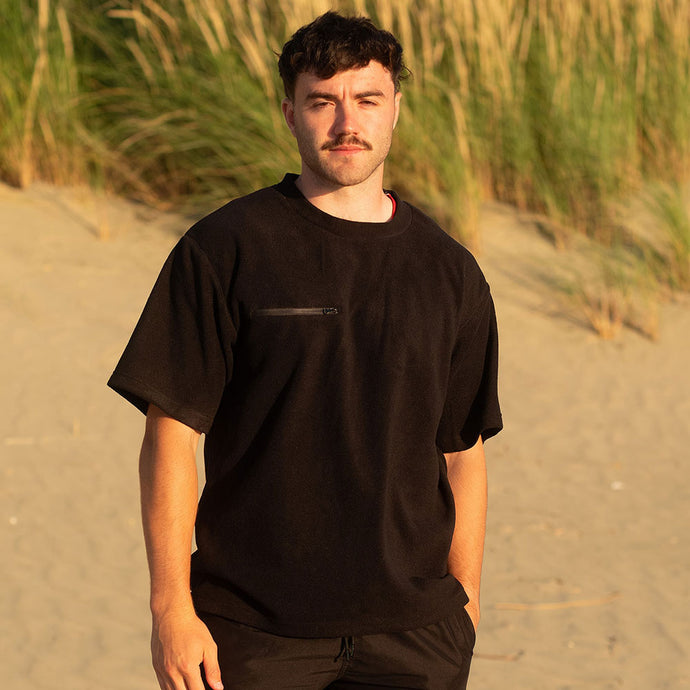 Close-up of a man wearing the Monowai Fleece Tee, showcasing the zippered chest pocket and side seams. Ideal for outdoor work, this tee offers durability and comfort with its breathable, recycled polyester fabric.