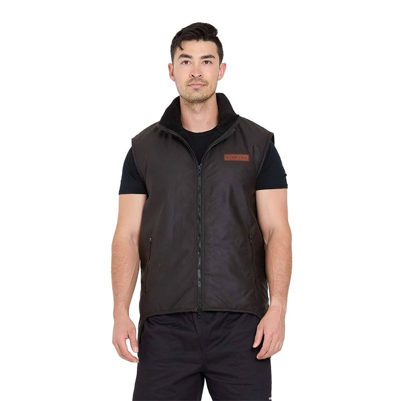 Load image into Gallery viewer, Male model wears the Kaiwaka Sleeveless Oilskin Vest, featuring a high collar, two zippered pockets, and a logo patch. Ideal for outdoor work, it's sherpa-lined, water-resistant, and durable.
