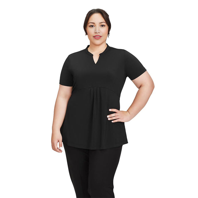Biz Womens Mali Stretch Tunic T-Top on a plus-size woman, featuring pleated front, longer hemline for maternity coverage, suitable for active work environments. She stands confidently, showcasing the tunic's functional design.