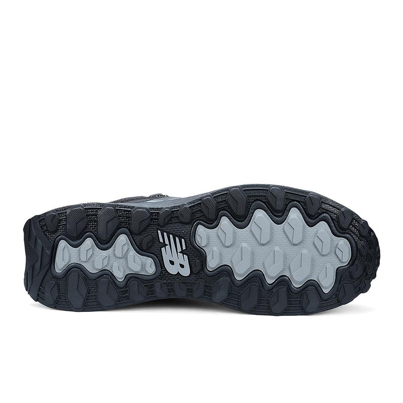 Load image into Gallery viewer, Underside of New Balance Womens Fresh Foam Cremorne Mid Safety Boot, Black/Grey, displaying textured black and gray lug pattern for traction, with molded NB logo, emphasizing durability and safety features.
