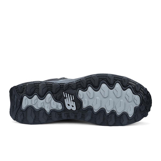 Underside of New Balance Womens Fresh Foam Cremorne Mid Safety Boot, Black/Grey, displaying textured black and gray lug pattern for traction, with molded NB logo, emphasizing durability and safety features.