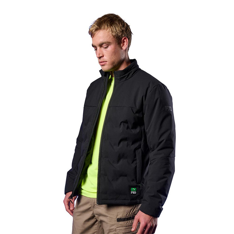 Load image into Gallery viewer, Model wearing FXD WO-5 Insulated Puffer Jacket with stitchless baffle design, featuring a reflective sleeve logo and secure pockets, styled over a neon T-shirt with cargo pants, embodying durable workwear.

