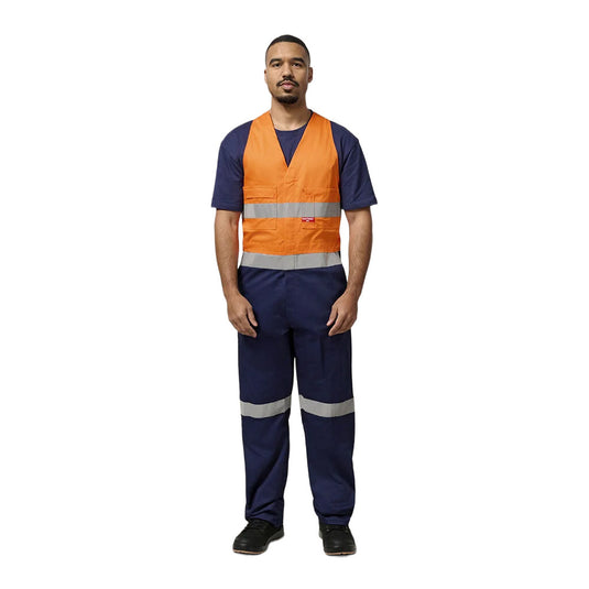Man modeling Hard Yakka Easy Action Hi Vis Cotton Bib Overall, featuring reflective tape, elastic back waist, non-spill pockets, and durable construction, ideal for visibility and functionality on work sites.