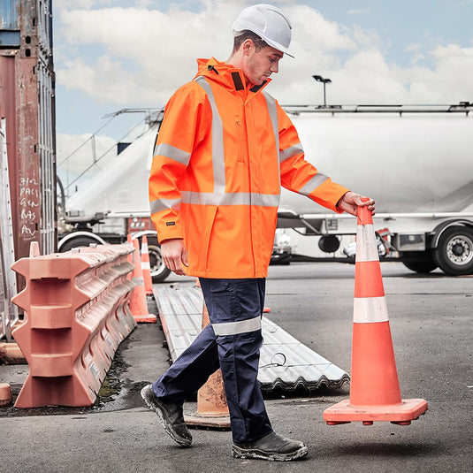 Syzmik Hi Vis TTMC-W23 X Back PU Rain Jacket features a durable waterproof design with an adjustable hood, storm cuffs, and reflective tape, ideal for workplace safety and protection.