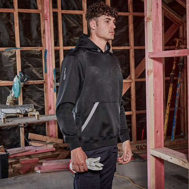 Syzmik Streetworx Water Resistant Hoodie worn by a man at a construction site, showcasing its durable fleece fabric, zippered kangaroo pockets, and pencil pocket on the arm for practicality.
